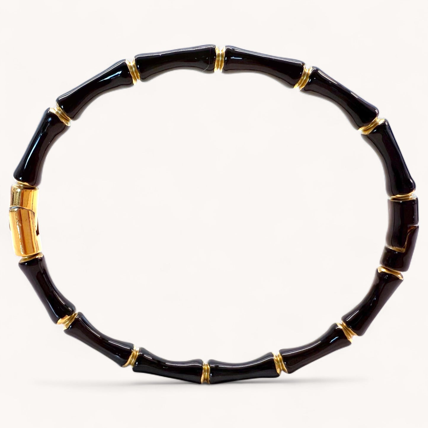 Close up image of 18k gold plated stainless steel bamboo bangle bracelets with high gloss black color enamel finish showing details of the geometric wood inspired nodes by Ashley Nicole Jewelry.