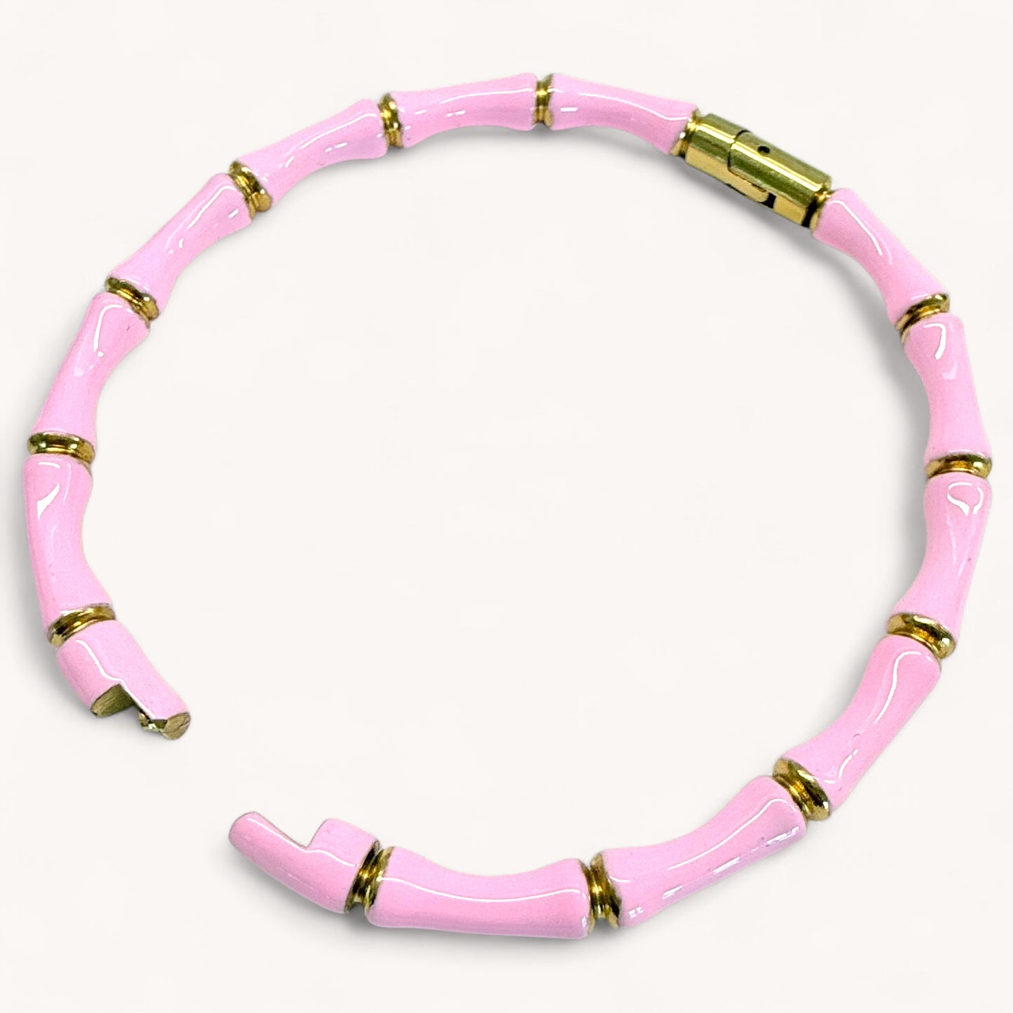 Close up image of an 18k gold plated stainless steel bamboo bangle bracelet with pink enamel showing details of the geometric wood inspired nodes and a glossy color finish by Ashley Nicole Jewelry.