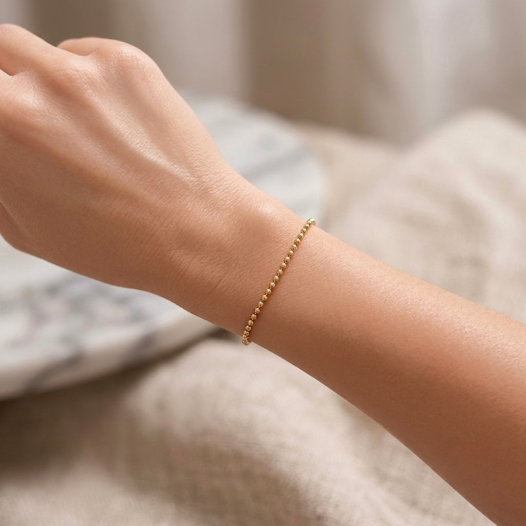 Model wearing a single 14K gold-filled 2mm ball chain bracelet, highlighting its delicate fit and daily wear profile.