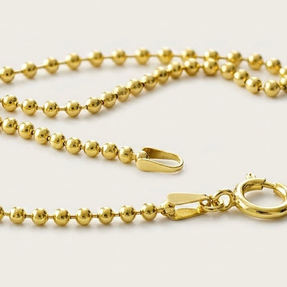Macro studio close-up of the 14K gold-filled ball chain, focusing on the smooth bead texture and sturdy spring-ring closure.