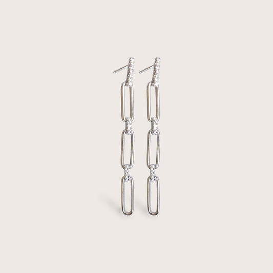 A pair of silver chain earrings with small diamonds. The earrings are long and dangle. The earrings are worn in the left ear.