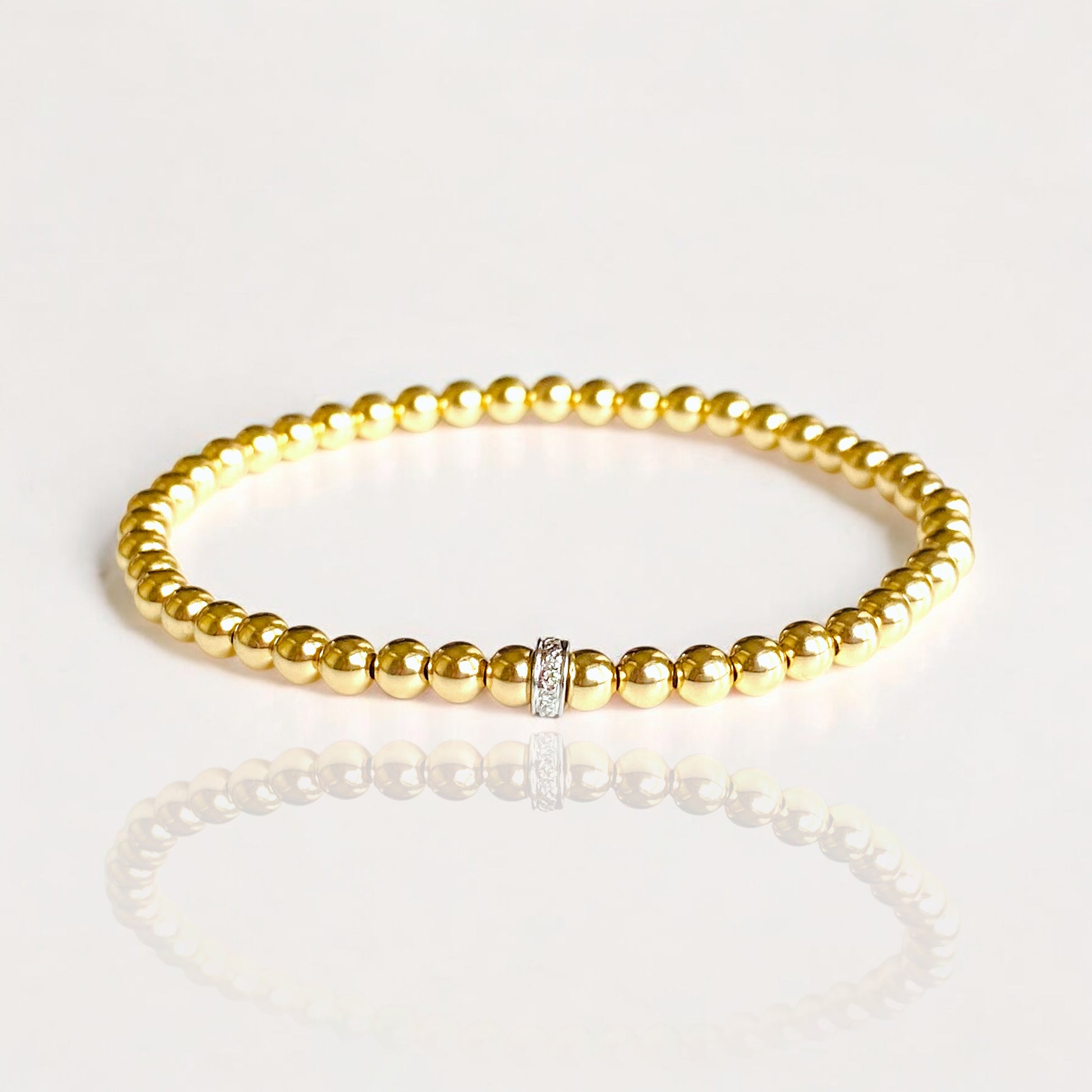 Premium 14K Gold Beads: Each 4mm &nbsp;bead is crafted from high-quality 14K yellow gold, offering a radiant and durable finish.
Single Diamond Accent: The bracelet is adorned with one diamond-accented Roundel, adding a touch of luxury and brilliance.
Elastic Stretch Fit: Designed with an elastic cord, this bracelet provides a comfortable and flexible fit for various wrist sizes.
Handcrafted Quality: Meticulously handmade to ensure exceptional craftsmanship and attention to detail.
