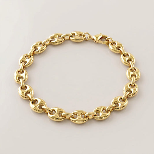 Gold puffed mariner bracelet with 8mm-wide oval links and a lobster clasp, arranged on a neutral surface.