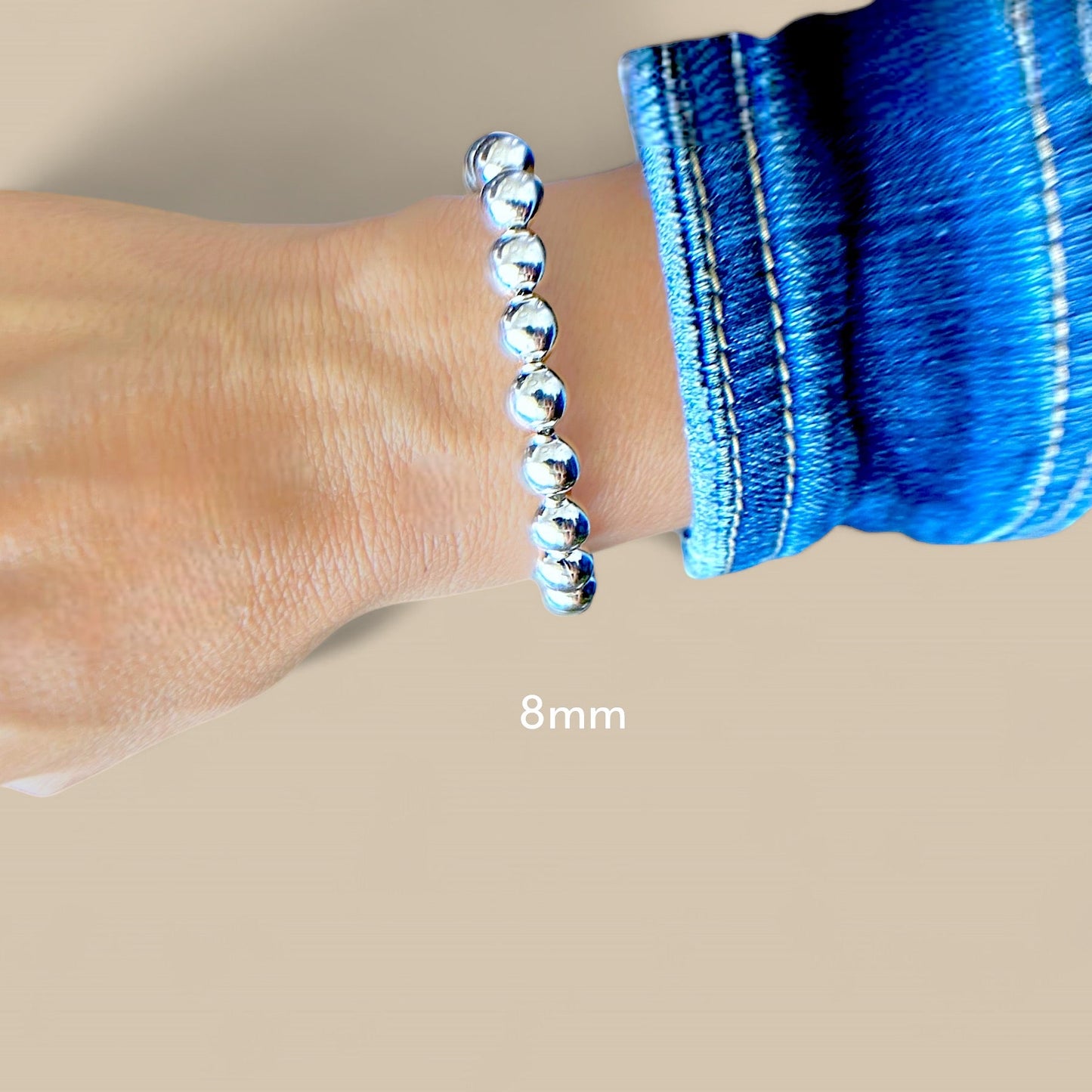 A 8mm silver beaded chain bracelet with a lobster claw closure.on a model