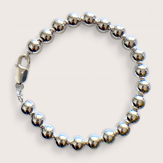 Close up of a polished 8mm sterling silver ball bead bracelet with a large lobster claw clasp on a white background by Ashley Nicole Jewelry