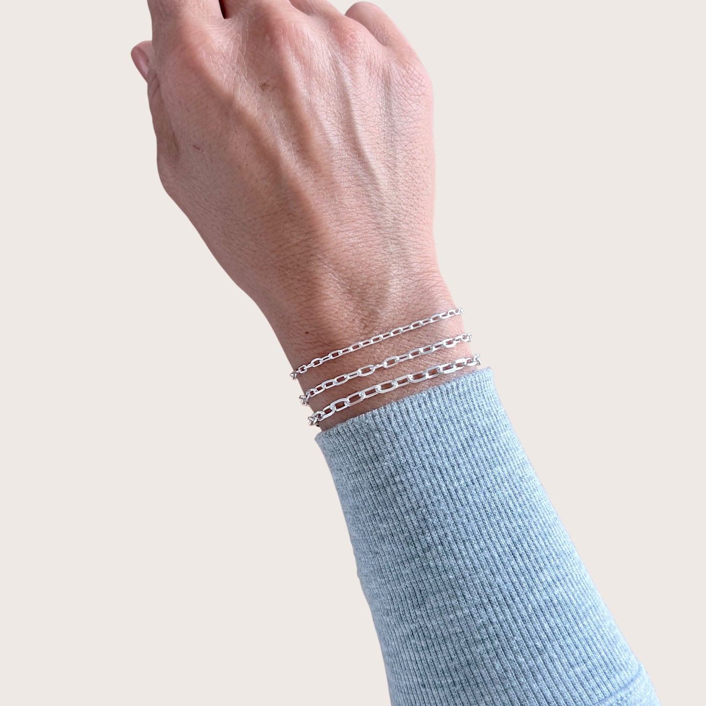Close-up lifestyle photo of a model wearing a waterproof solid 925 sterling silver marina anchor link chain bracelet styled as a daily wrist stacker by Ashley Nicole Jewelry.