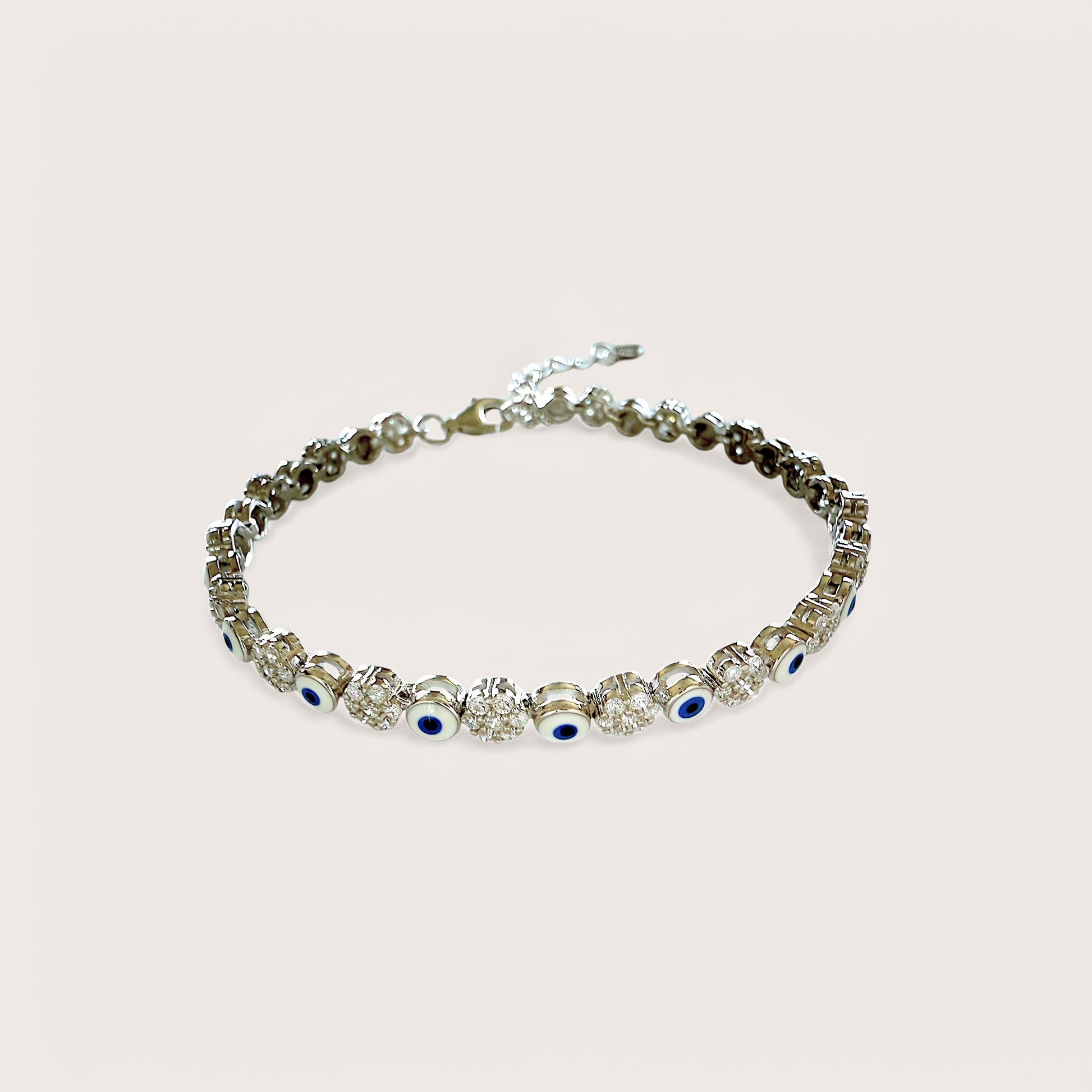An adjustable sterling silver bracelet featuring a dark blue evil eye and clusters of clear cubic zirconia stones.