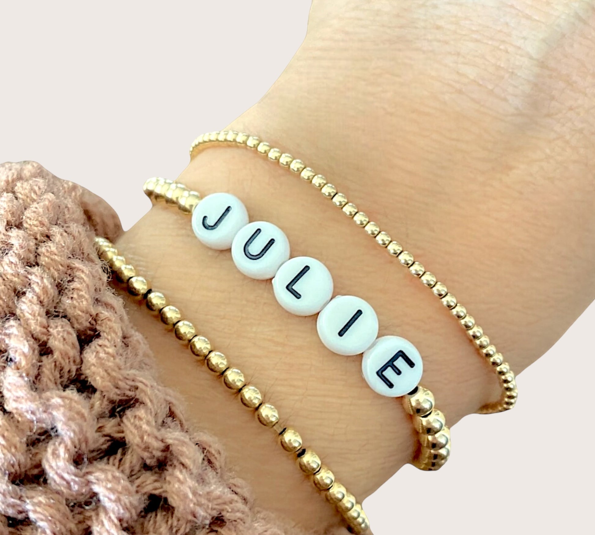 Close up of personalized beaded name bracelet and gold and white beads