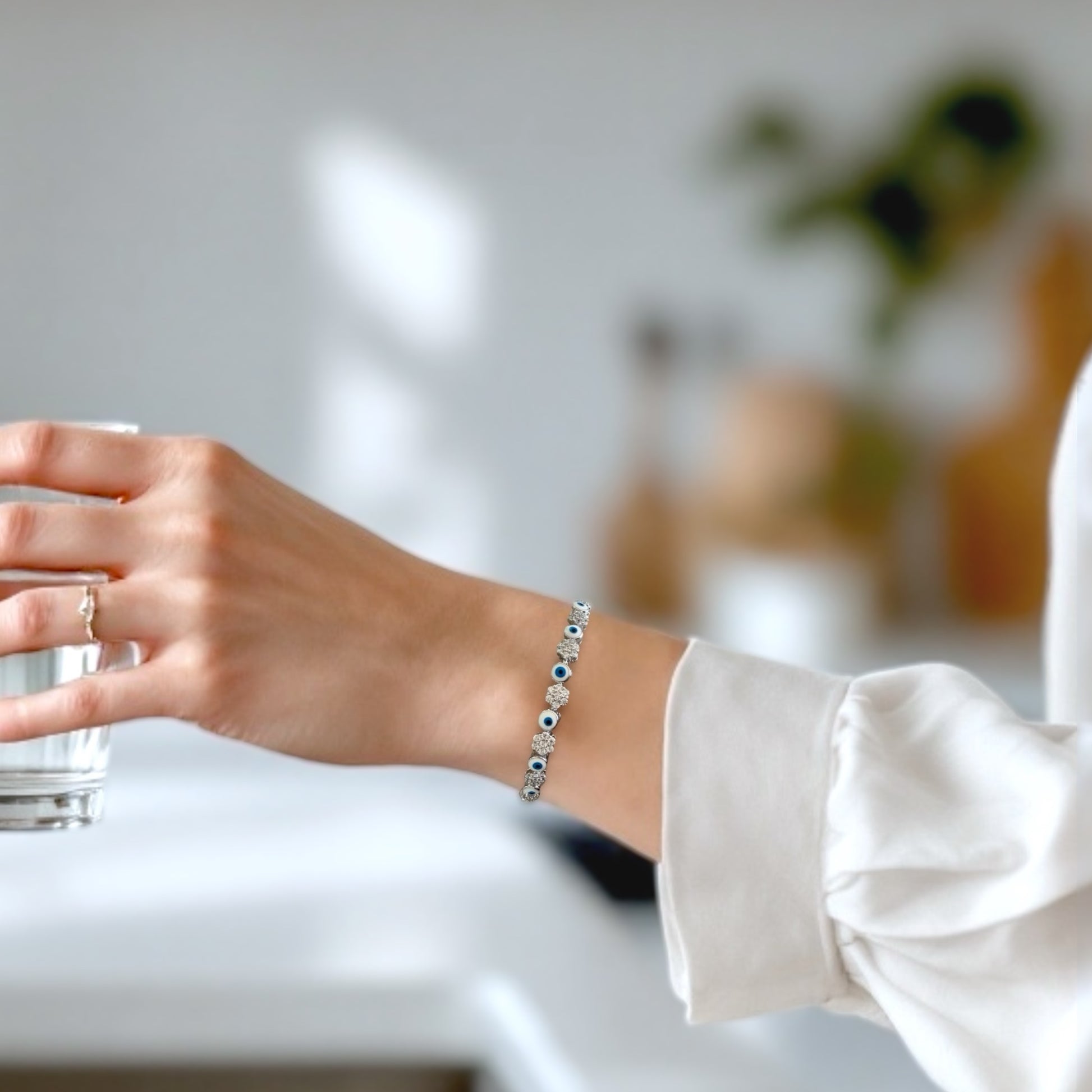Model wearing a sterling silver bracelet featuring a dark blue evil eye and clusters of clear cubic zirconia stones.