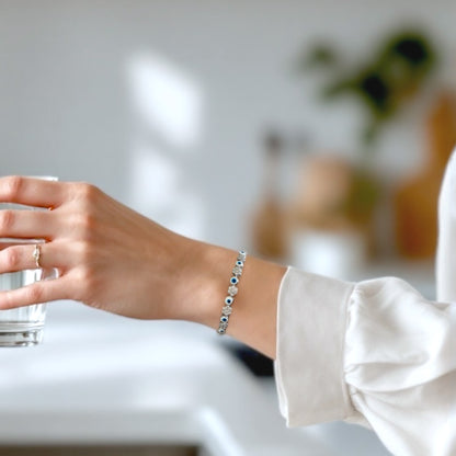Model wearing a sterling silver bracelet featuring a dark blue evil eye and clusters of clear cubic zirconia stones.