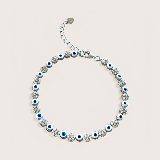 An adjustable sterling silver bracelet featuring a dark blue evil eye and clusters of clear cubic zirconia stones.