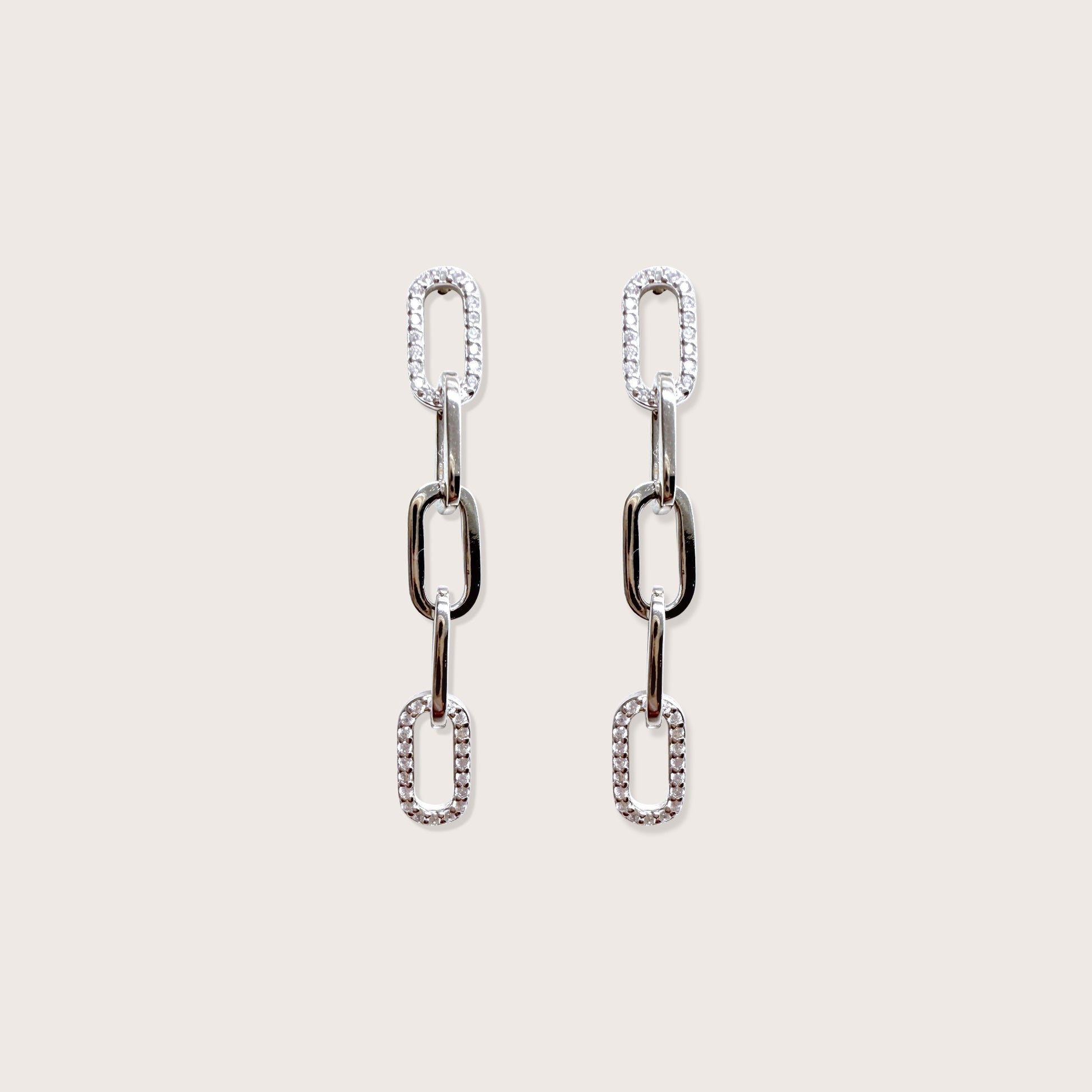 Pair of silver chain-link earrings on a light beige background