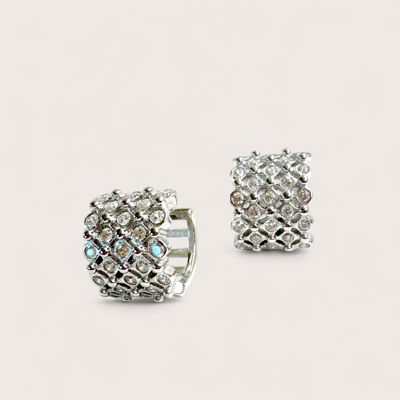 Pair of silver hoop earrings with clear gemstones on a light gray background