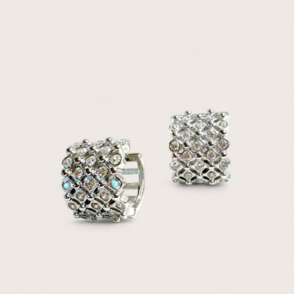 Pair of silver hoop earrings with clear gemstones on a light gray background
