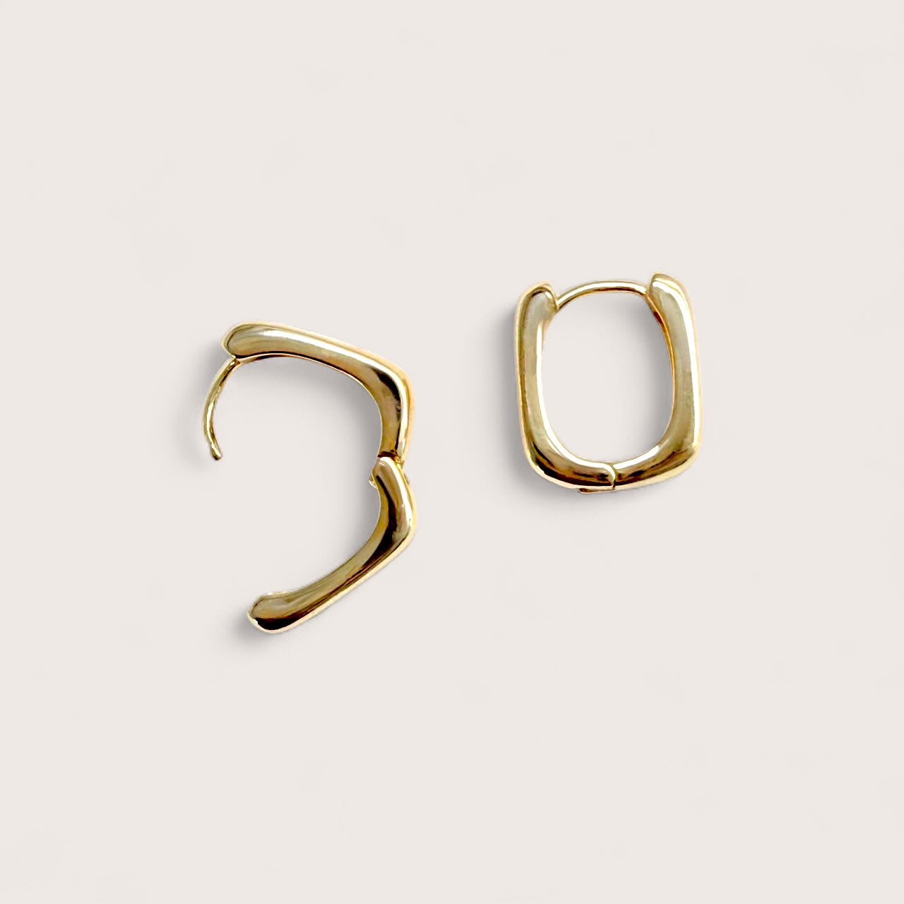 Crisp product photograph of the 18K gold plated chunky square huggie hoops, highlighting their mirror-bright finish and secure click-hinge snap closure.