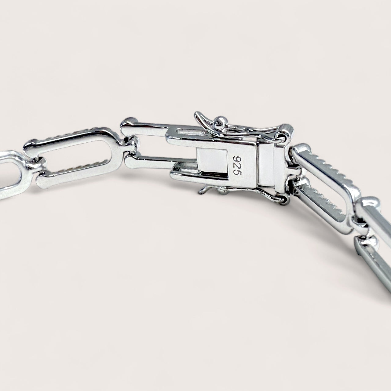 Close-up of a silver bracelet with a clasp on a light beige background