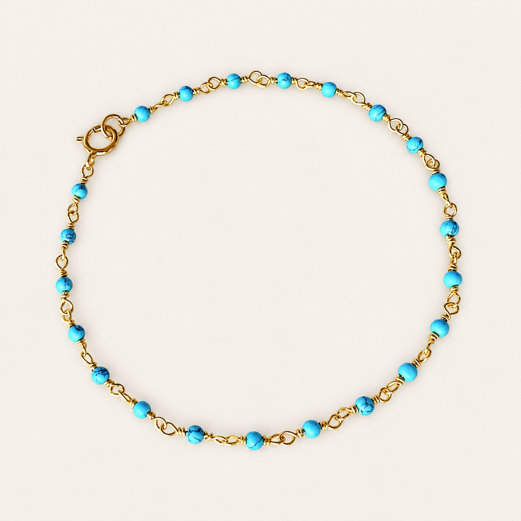 Turquoise bead rosary chain bracelet with gold-plated links and a spring-ring clasp, arranged in a circle on a beige background.