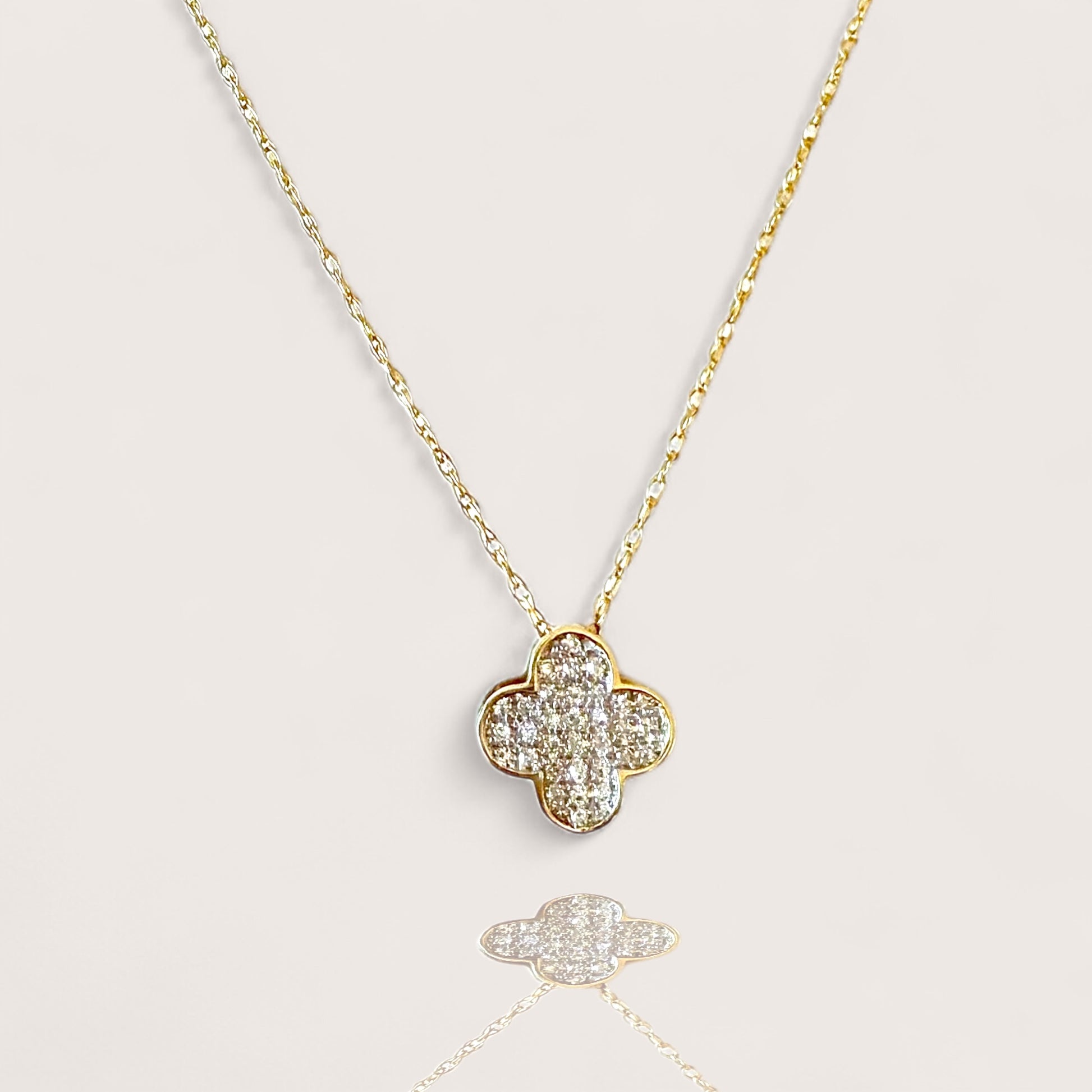 Gold necklace with a clover-shaped pendant on a light gray background