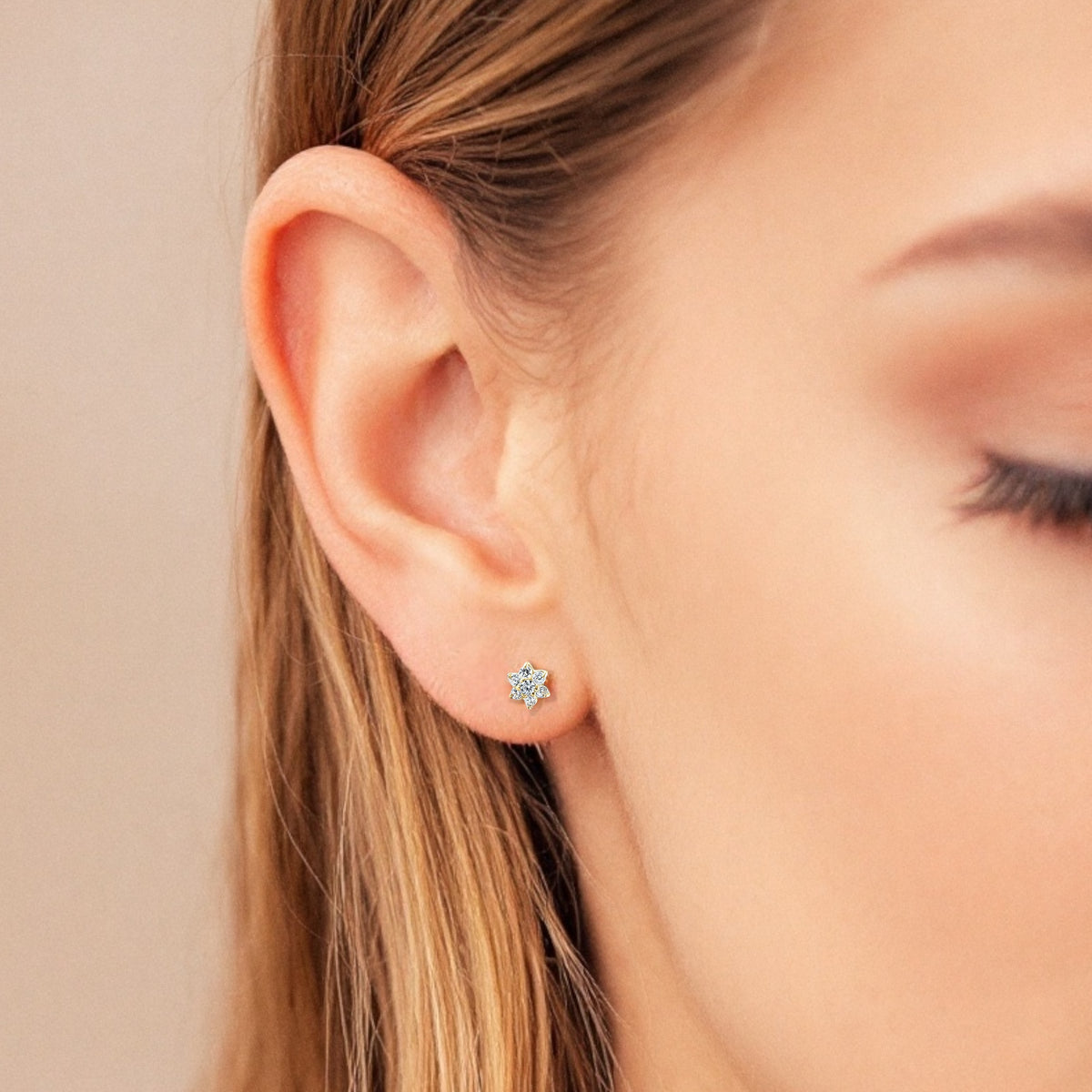 Small diamond flower stud worn in a second lobe piercing with other earrings
