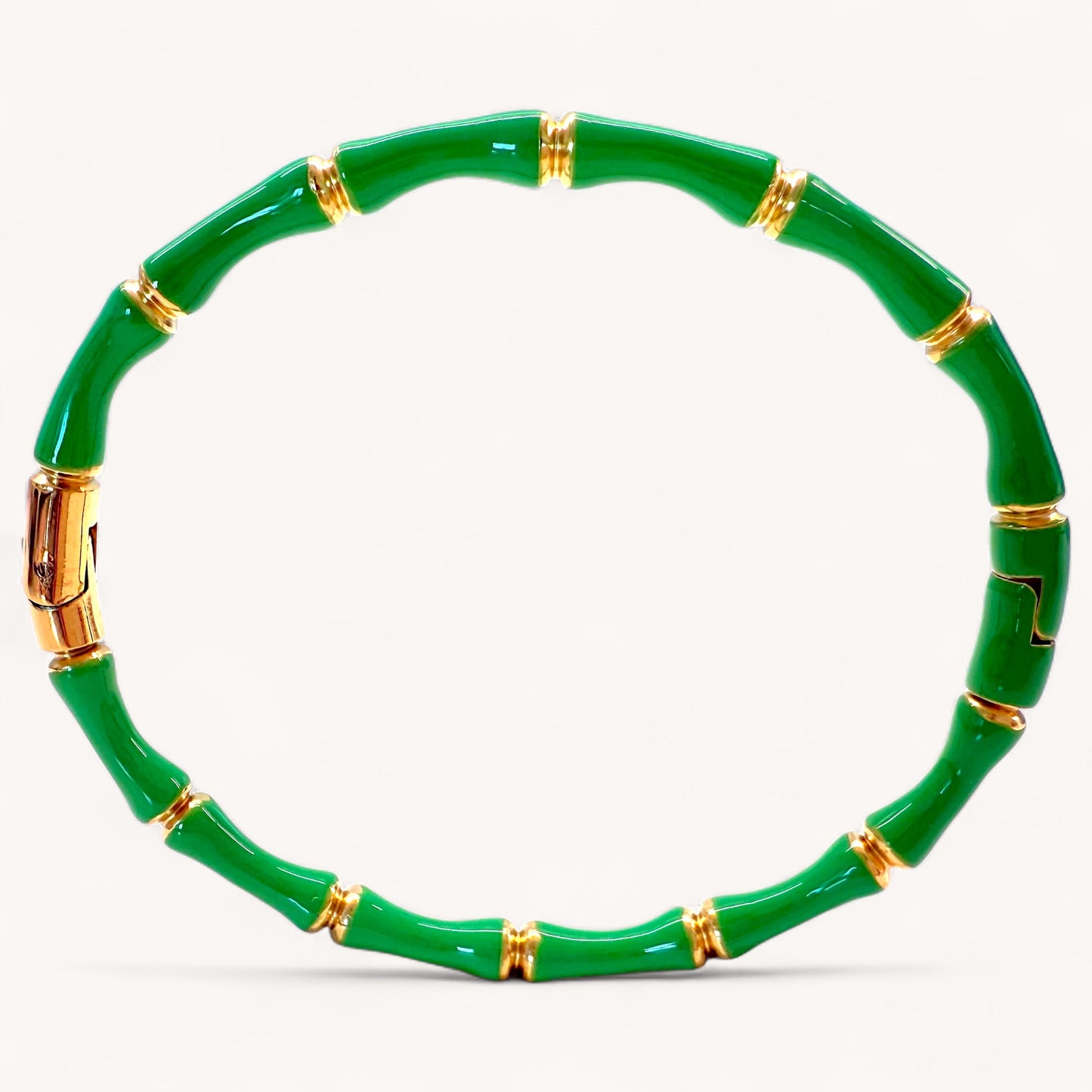 Close up image of 18k gold plated stainless steel bamboo bangle bracelets with high gloss emerald green color enamel finish showing details of the geometric wood inspired nodes by Ashley Nicole Jewelry.