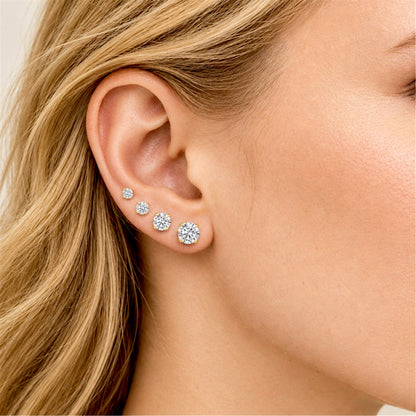 Close-up of a female model wearing four graduated CZ stud earrings with yellow gold four-prong settings.