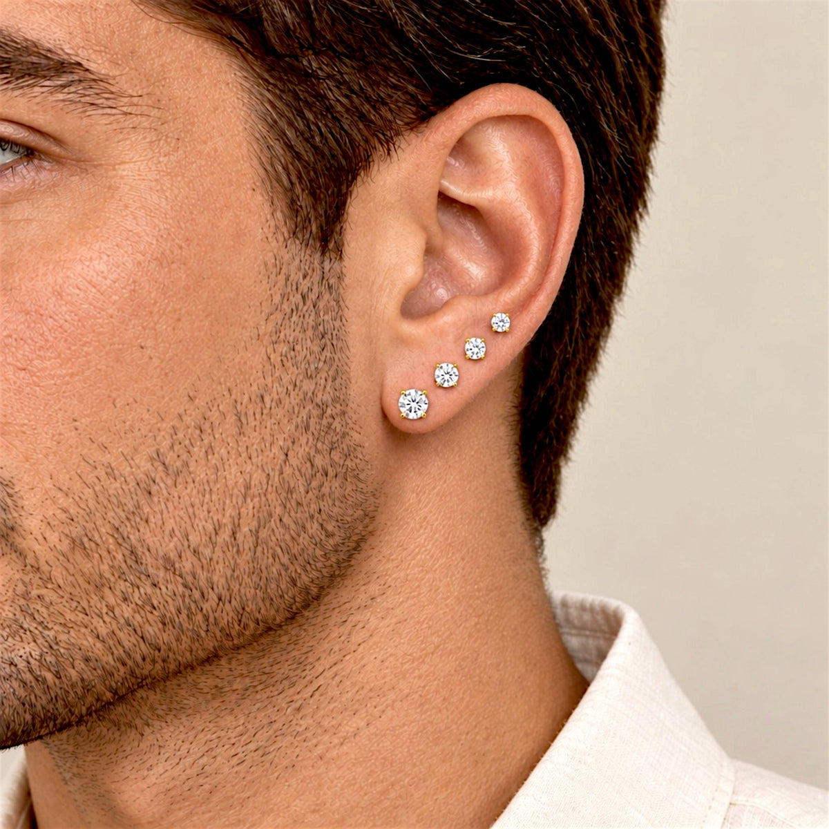 Close-up of a male model wearing four graduated CZ stud earrings along the earlobe.