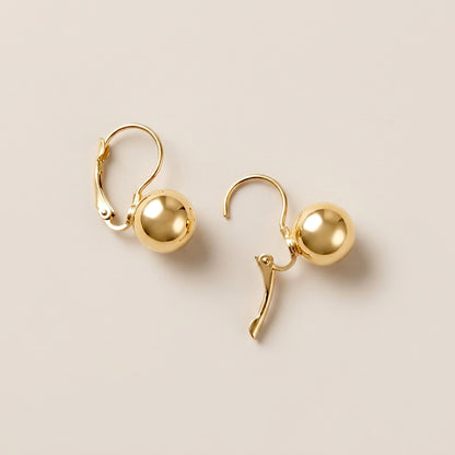 Two gold ball drop earrings shown with one lever-back closure open and the other closed