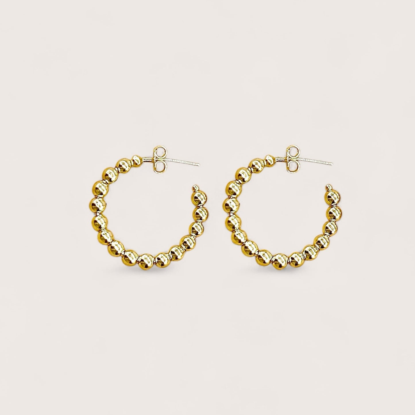A pair of 25mm dainty 18K gold plated beaded hoop earrings showcasing a continuous row of polished gold beads on a clean white background.