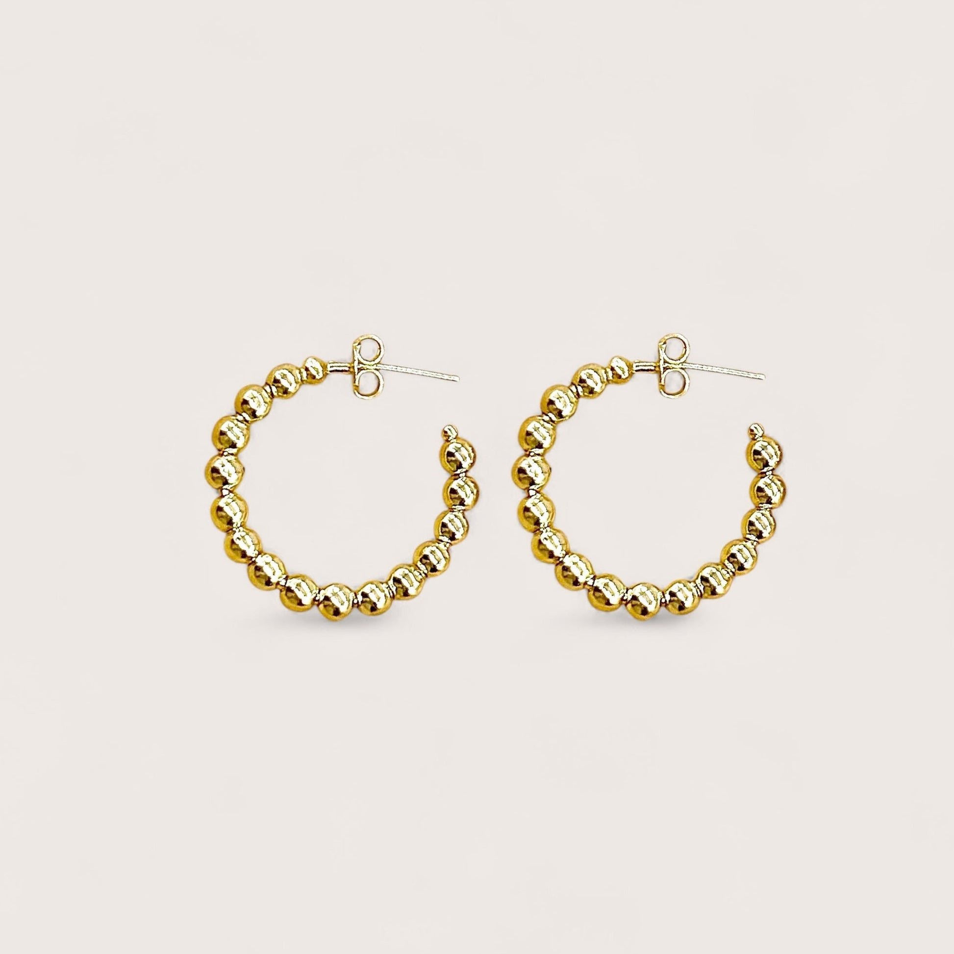A pair of 25mm dainty 18K gold plated beaded hoop earrings showcasing a continuous row of polished gold beads on a clean white background.