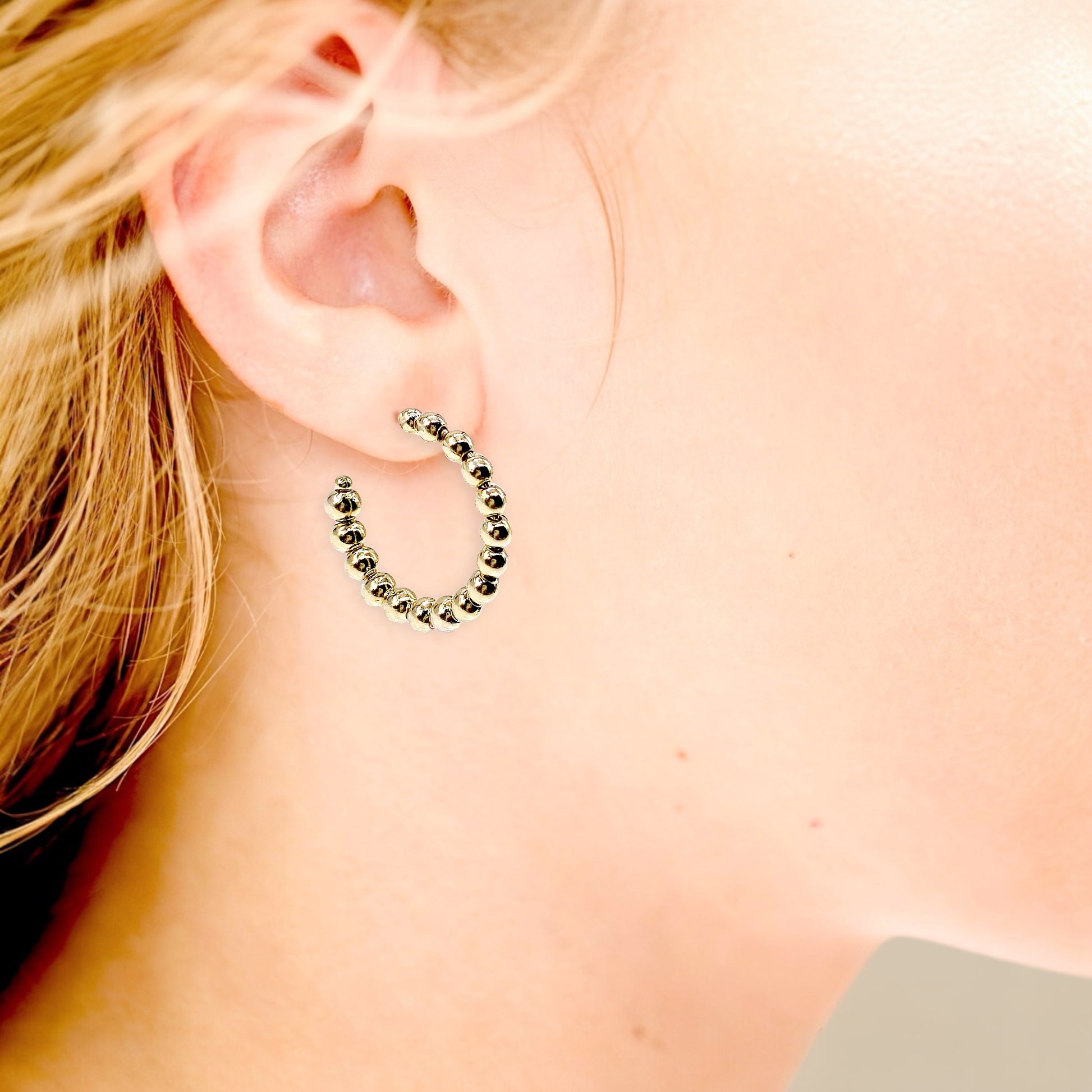 The Ashley Nicole Jewelry 18K gold plated 1-inch beaded hoop earrings styled on a model as an everyday staple look.