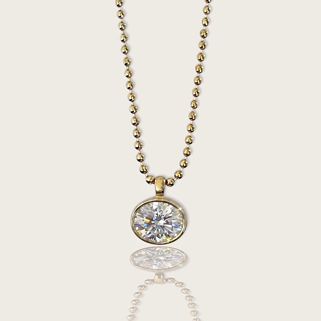 18K gold PVD stainless steel horizontal oval bezel-set cubic zirconia pendant necklace on a 2mm beaded ball chain by Ashley Nicole Jewelry, front view with reflection