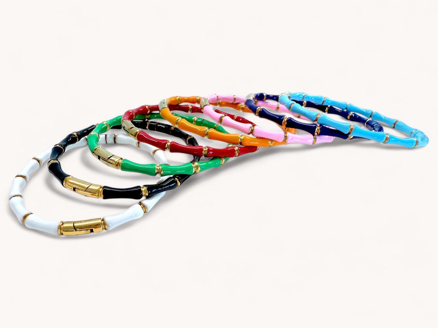 Close up view of 18K Gold Bamboo Bangle Bracelet on a white background, shown in white, black, emerald green, red, orange, pink, navy and turquoise