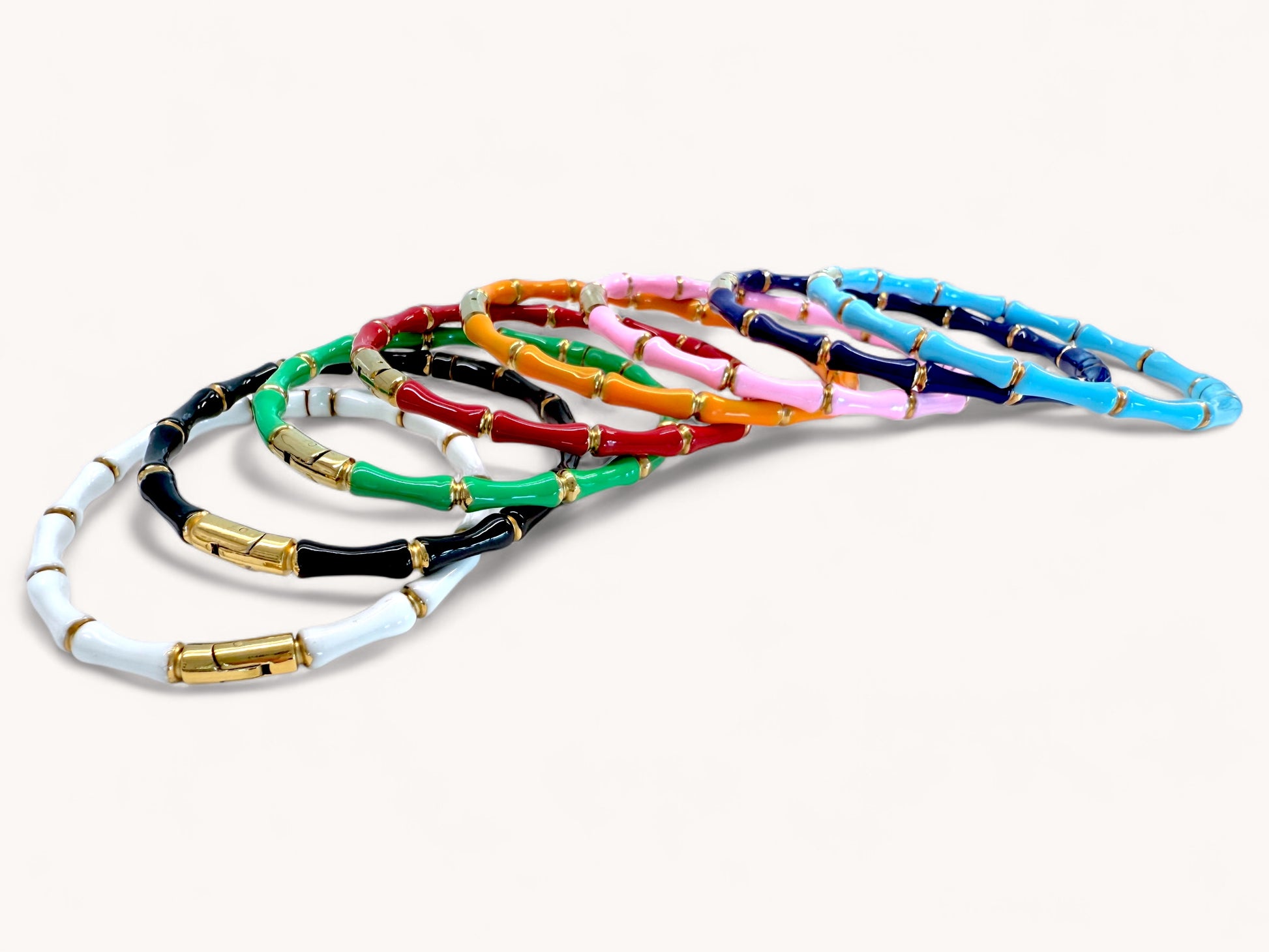 Close up view of 18K Gold Bamboo Bangle Bracelet on a white background, shown in white, black, emerald green, red, orange, pink, navy and turquoise