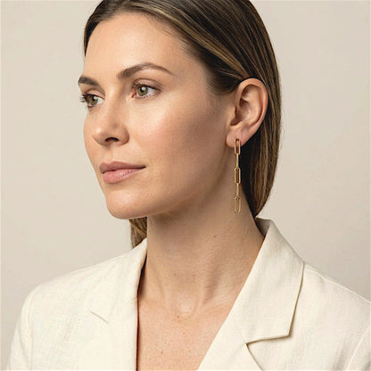 Model in an ivory jacket wearing gold filled paperclip dangle earrings, with her hair tucked behind her ear.
