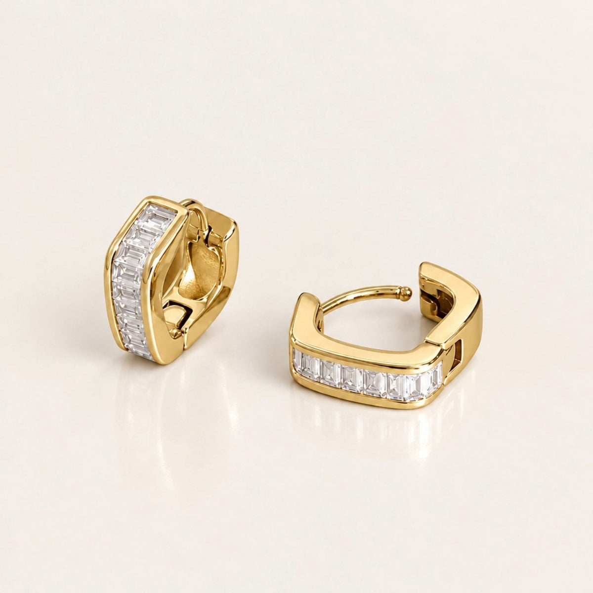 Gold-tone hex baguette huggie hoop pair with one upright and one lying open to show the curved post and hinged closure.