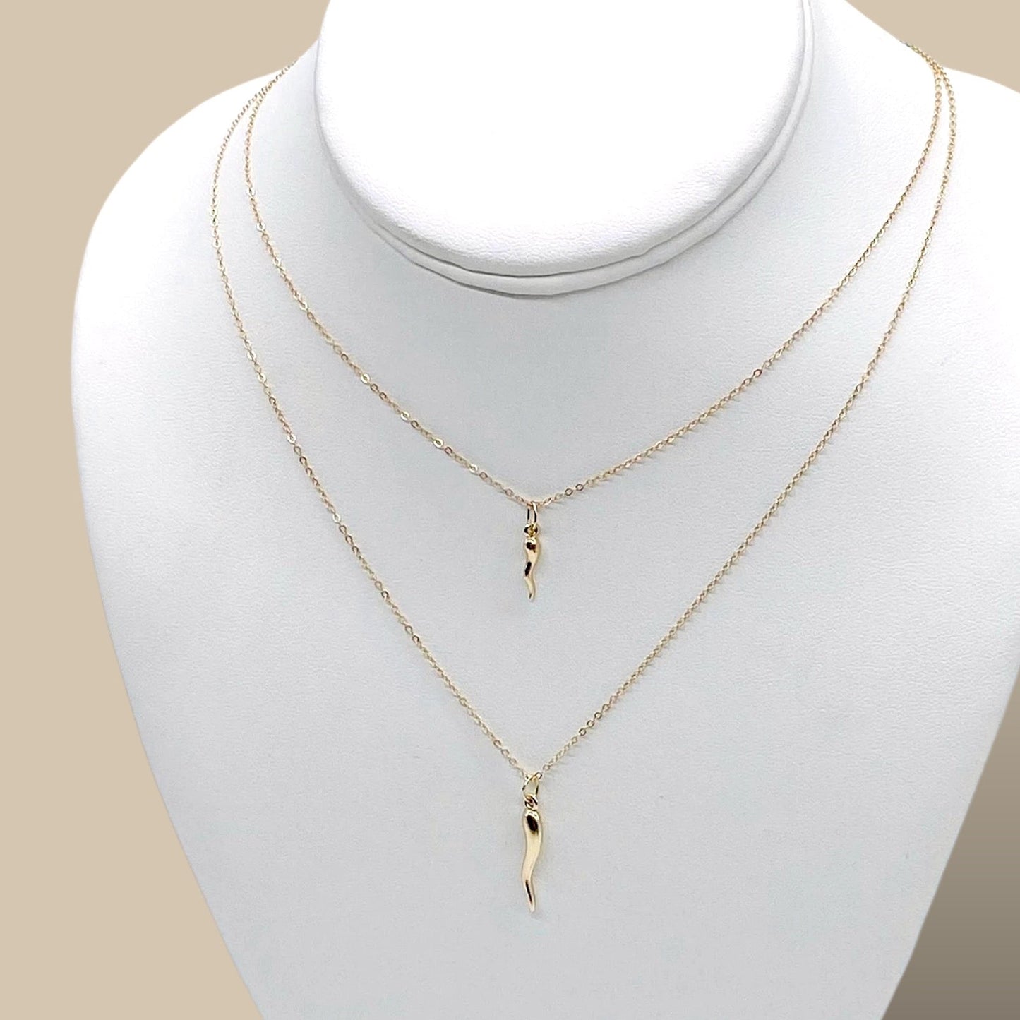 White jewelry bust displaying the layered proportions of the 14-inch through 20-inch 14K gold filled cornicello horn charm necklaces.