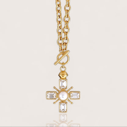 Front-facing studio view of the gold Maltese cross front toggle necklace featuring a heavy cable chain, emerald-cut crystals, and a central pearl accent.