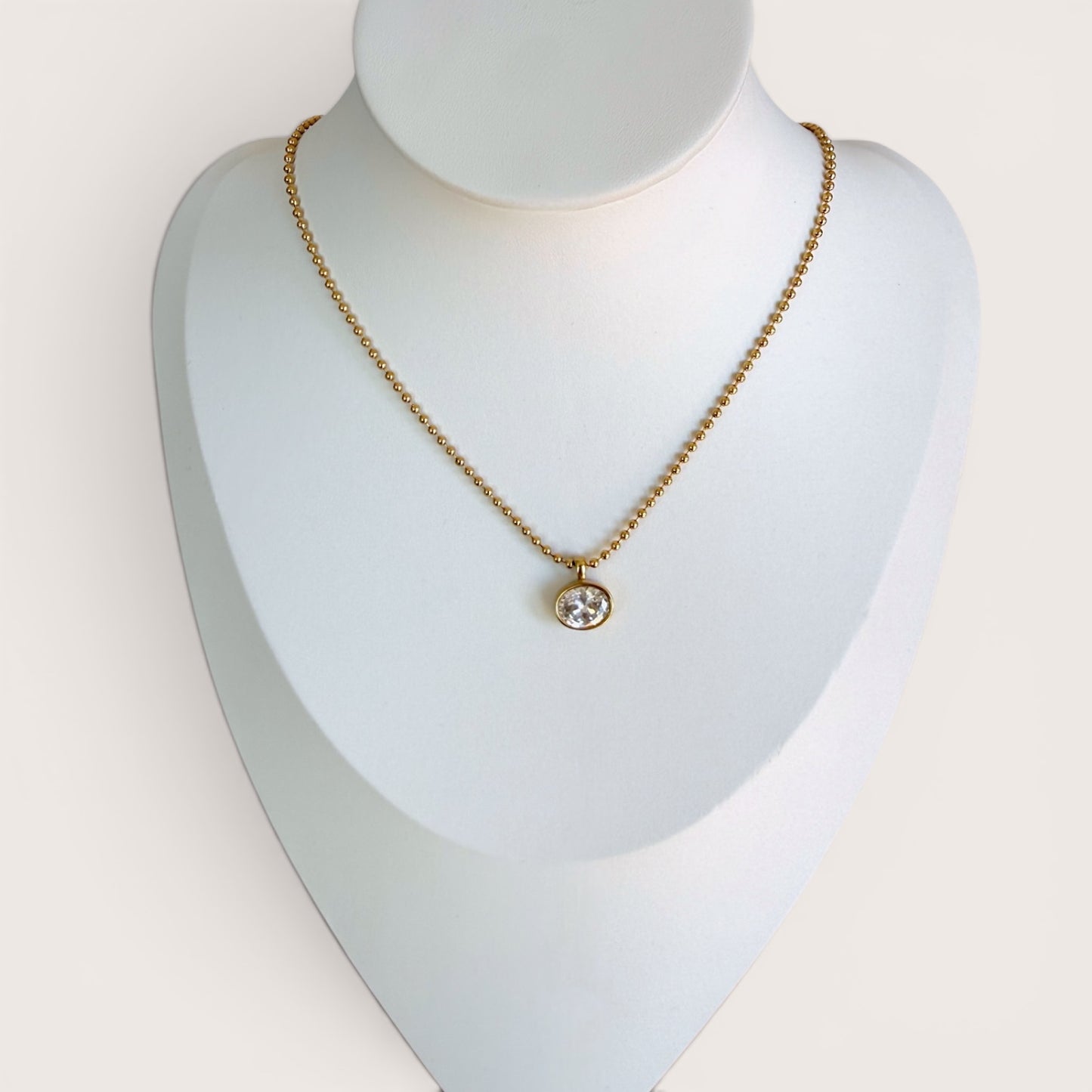18K gold PVD horizontal oval CZ necklace displayed on a professional white jewelry mannequin bust, full view.