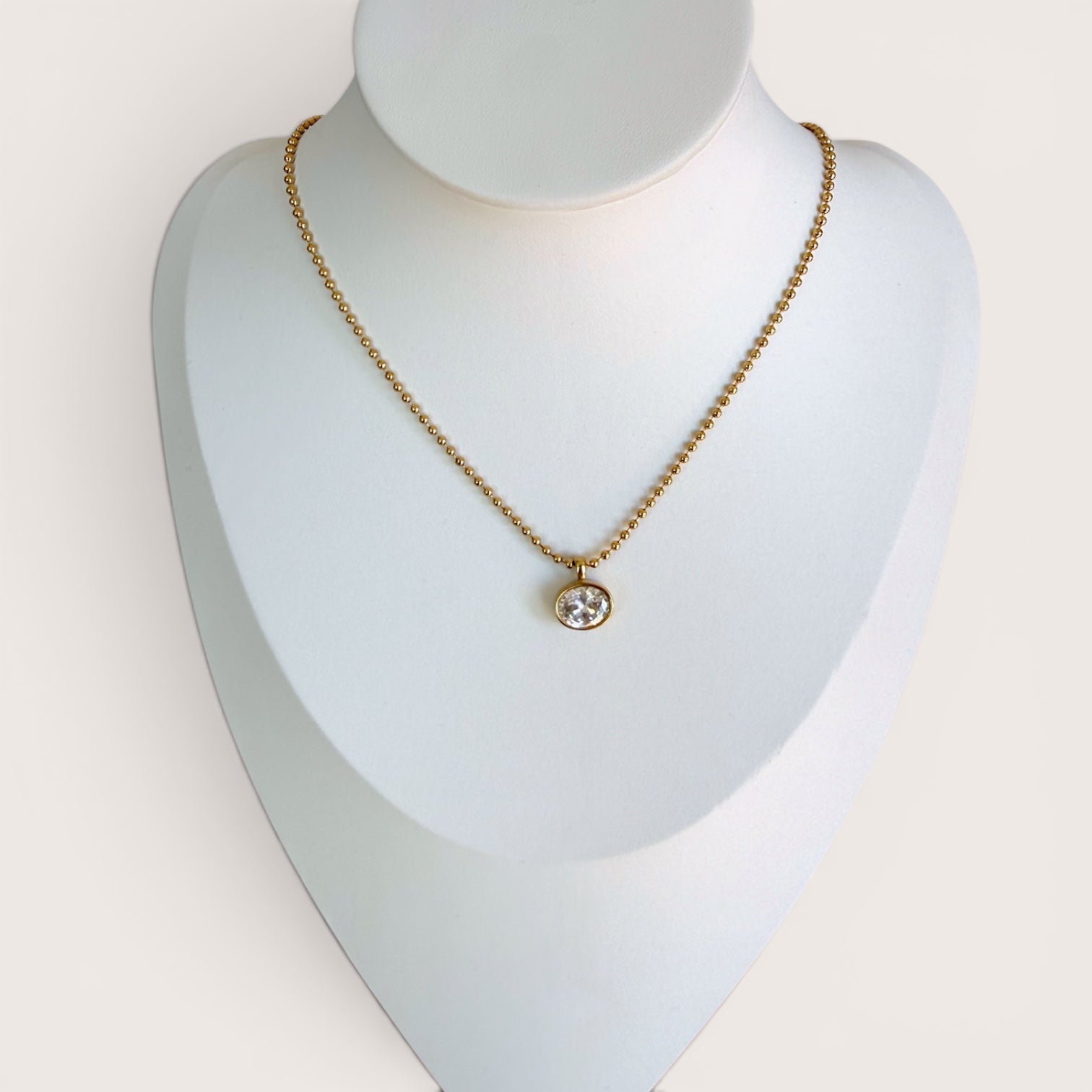 18K gold PVD horizontal oval CZ necklace displayed on a professional white jewelry mannequin bust, full view.
