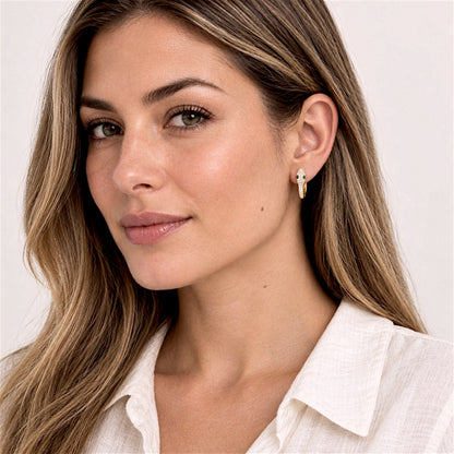 Lighter-haired model in an ivory blouse wearing a gold pavé snake huggie hoop, with her hair tucked behind her ear.