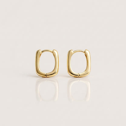 Pair of gold rectangular huggie earrings shown closed on a neutral background