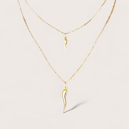 Layered display of the small and large 14K gold filled cornicello Italian horn pendant necklaces by Ashley Nicole Jewelry against a soft cream background.