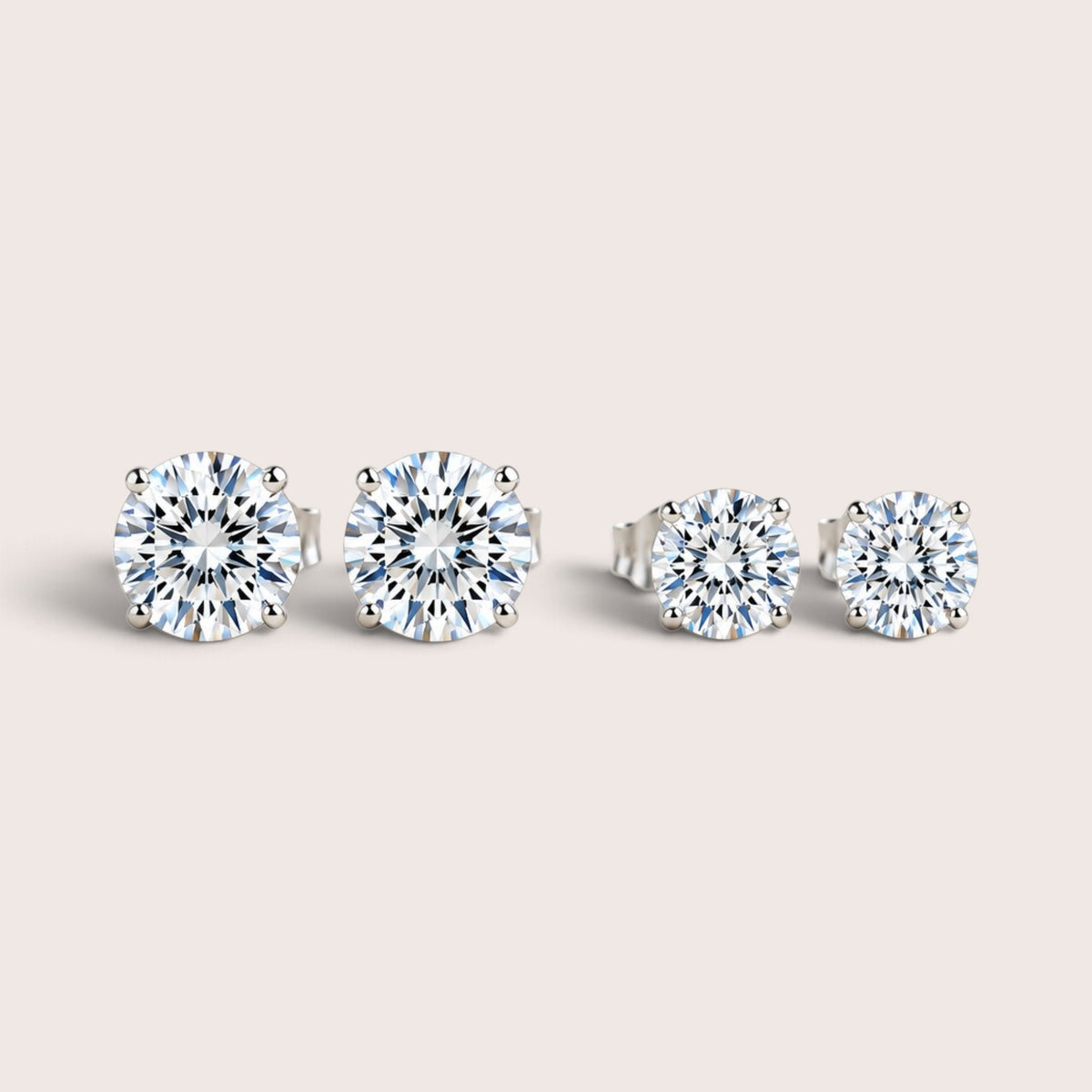 Two pairs of round moissanite stud earrings in silver settings, with the larger pair on the left and smaller pair on the right.