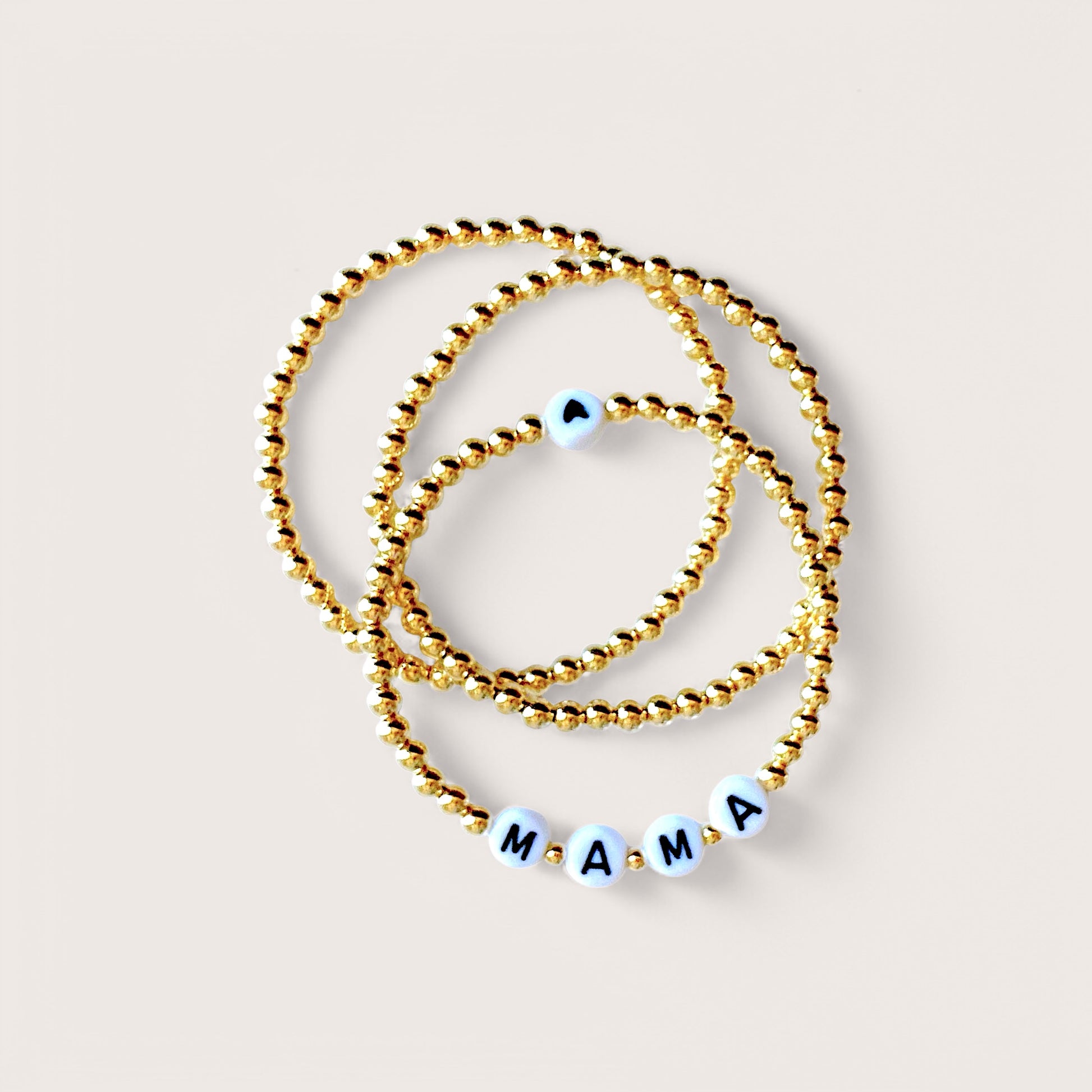 Close up of a gold beaded bracelet with MAMA letter beads  and heart bead 