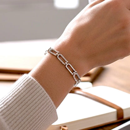 Sterling Silver Pave U Link chain bracelet on a wrist with books and a tablet in the background