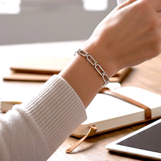 Sterling Silver Pave U Link chain bracelet on a wrist with books and a tablet in the background