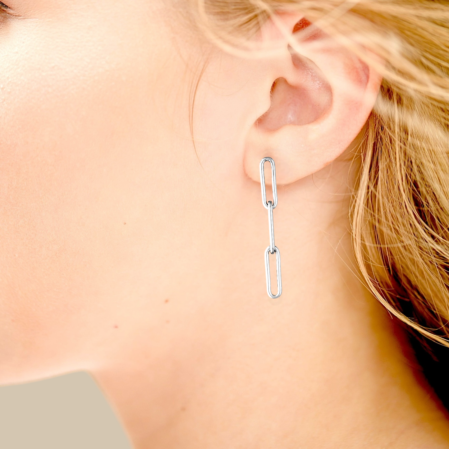 Lifestyle photo of long silver paperclip chain earrings styled with layered necklaces