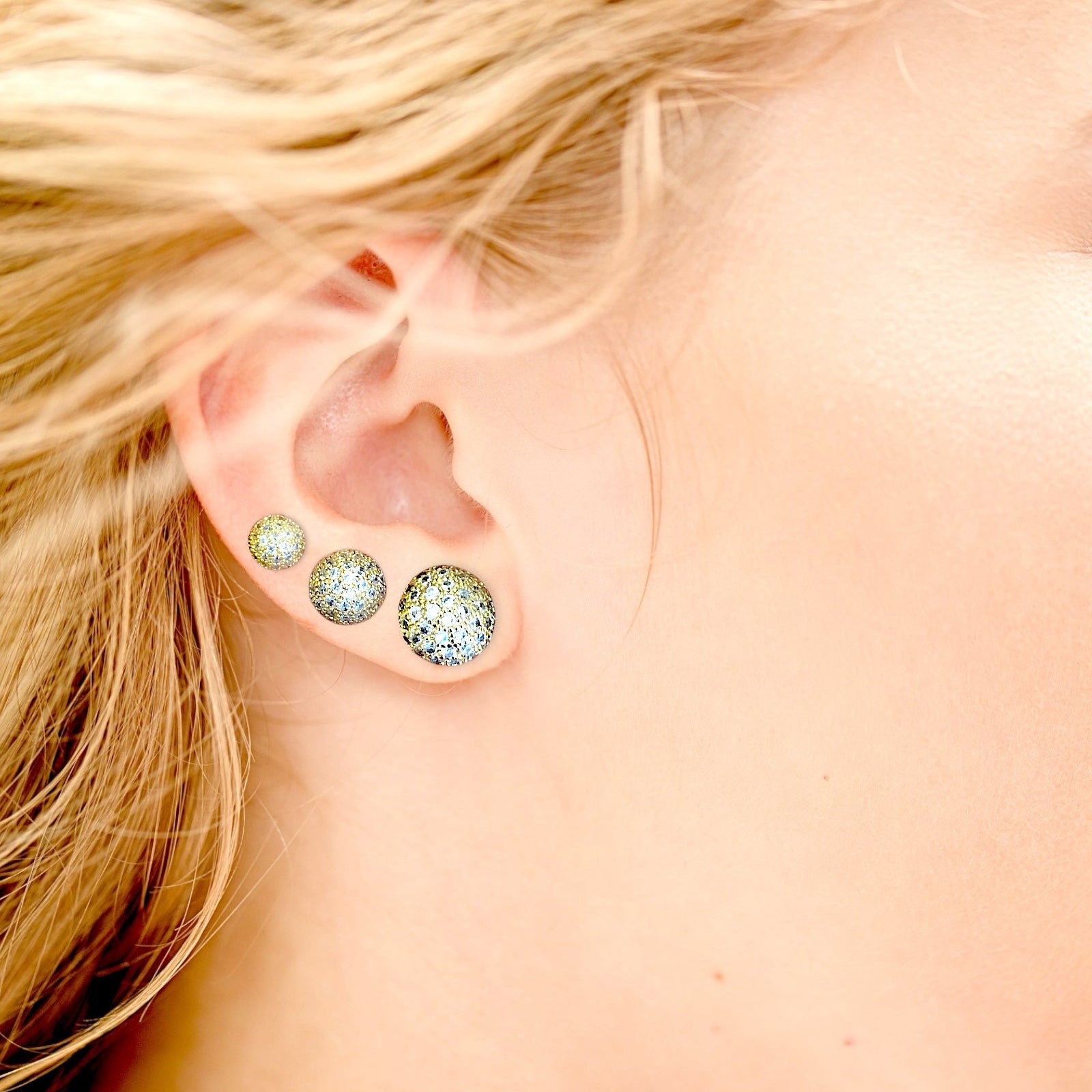 Close-up of gold pave disco bal on ear wearing three sparkling earrings in the various sizes