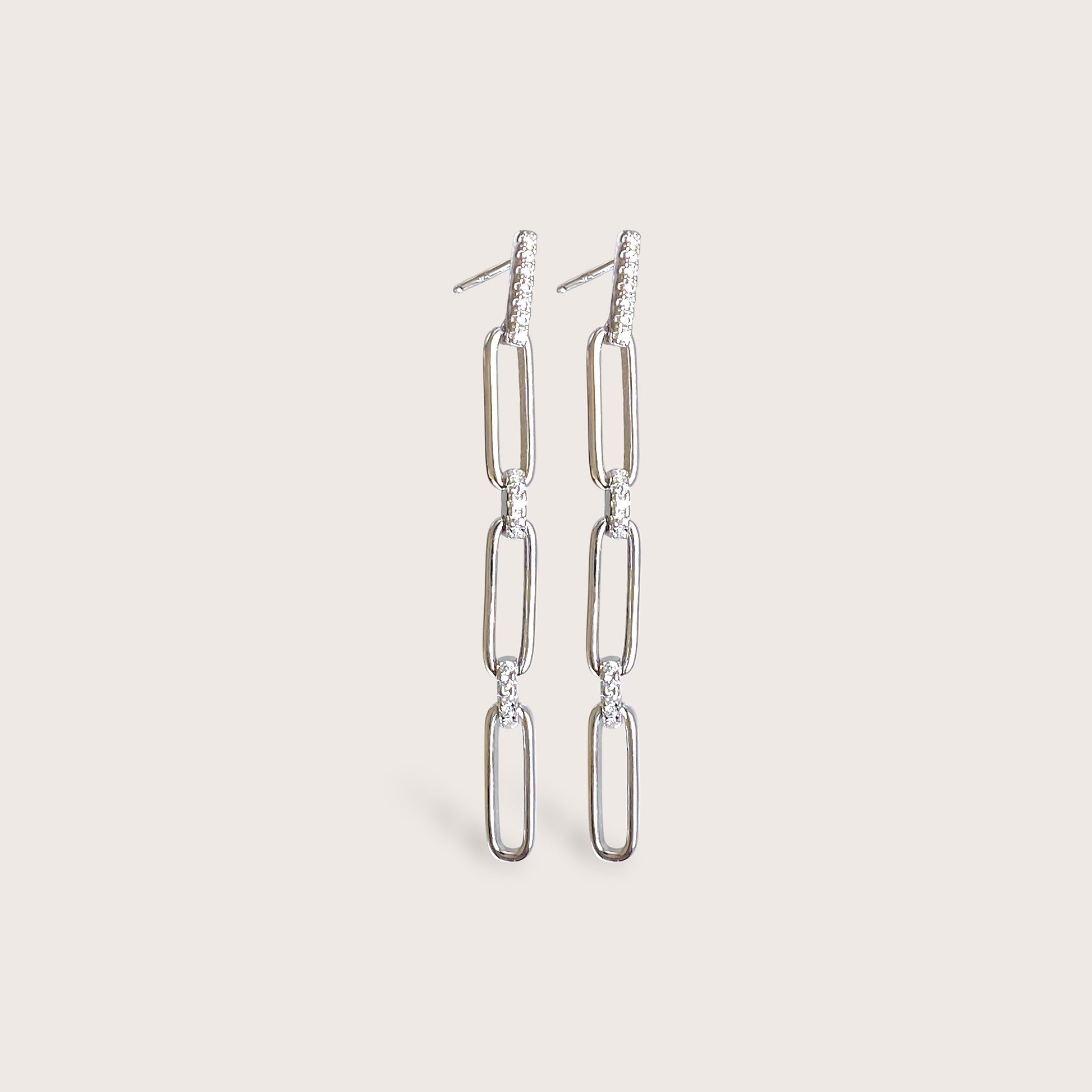 A pair of silver chain earrings with small diamonds. The earrings are long and dangle. The earrings are worn in the left ear.