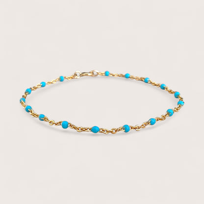 This high-quality Vibrant Turquoise Gold Chain Bracelet is made with 1.8mm delicate enamel beads and strong 14K gold fill. It's perfect for everyday wear, and can even be worn in the shower without losing its shine or color. This one-of-a-kind bracelet is handmade in sunny Laguna Beach, CA and comes in customizable sizes for everyone from newborns to adults. It's a fun and functional gift suitable for any occasion!